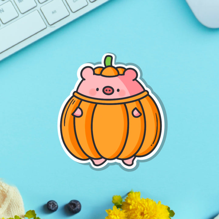 Pig dressed as pumpkin vinyl sticker on blue table with keyboard