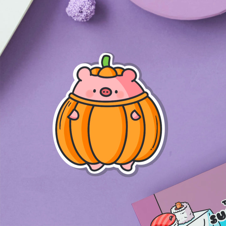 Pig dressed as pumpkin vinyl sticker on purple table