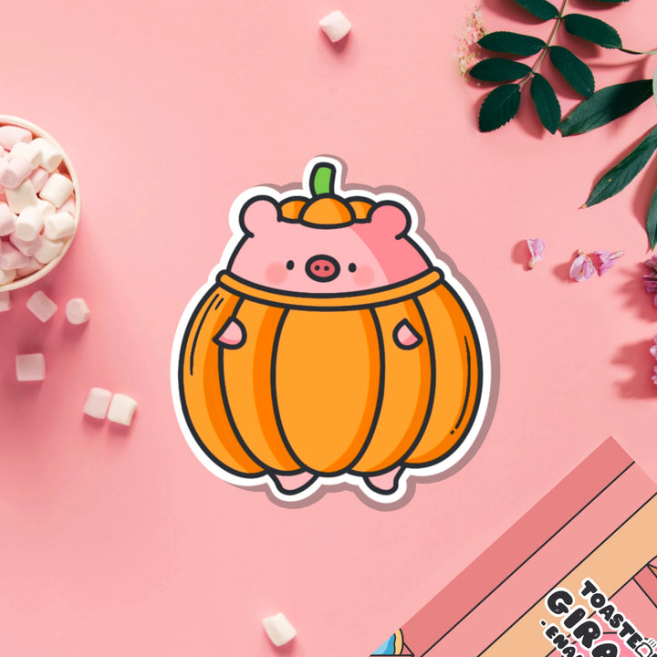 Pig dressed as pumpkin vinyl sticker on pink table