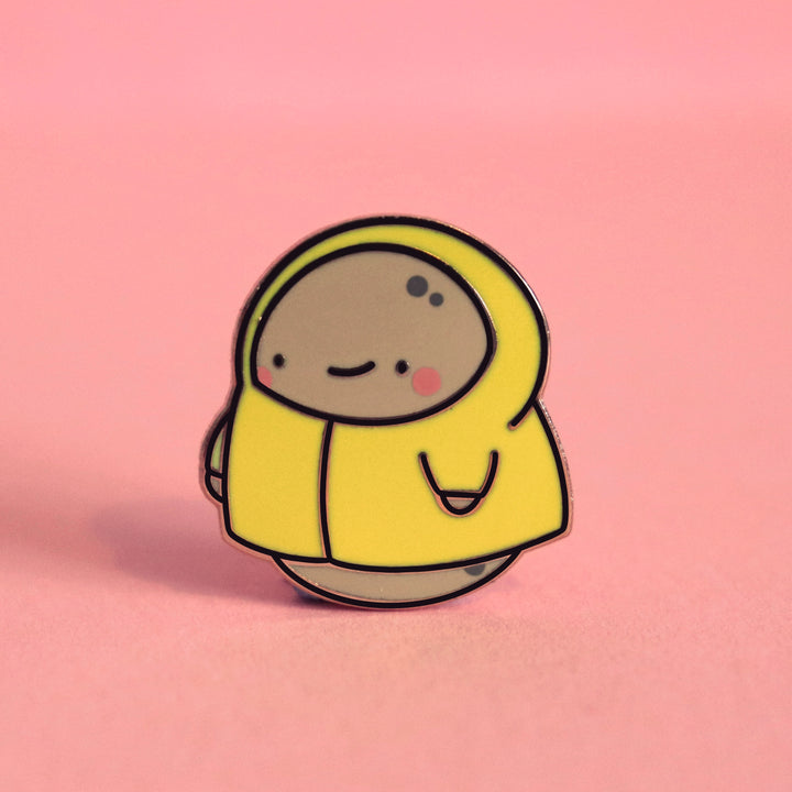 Potato in a raincoat enamel pin on pink desk