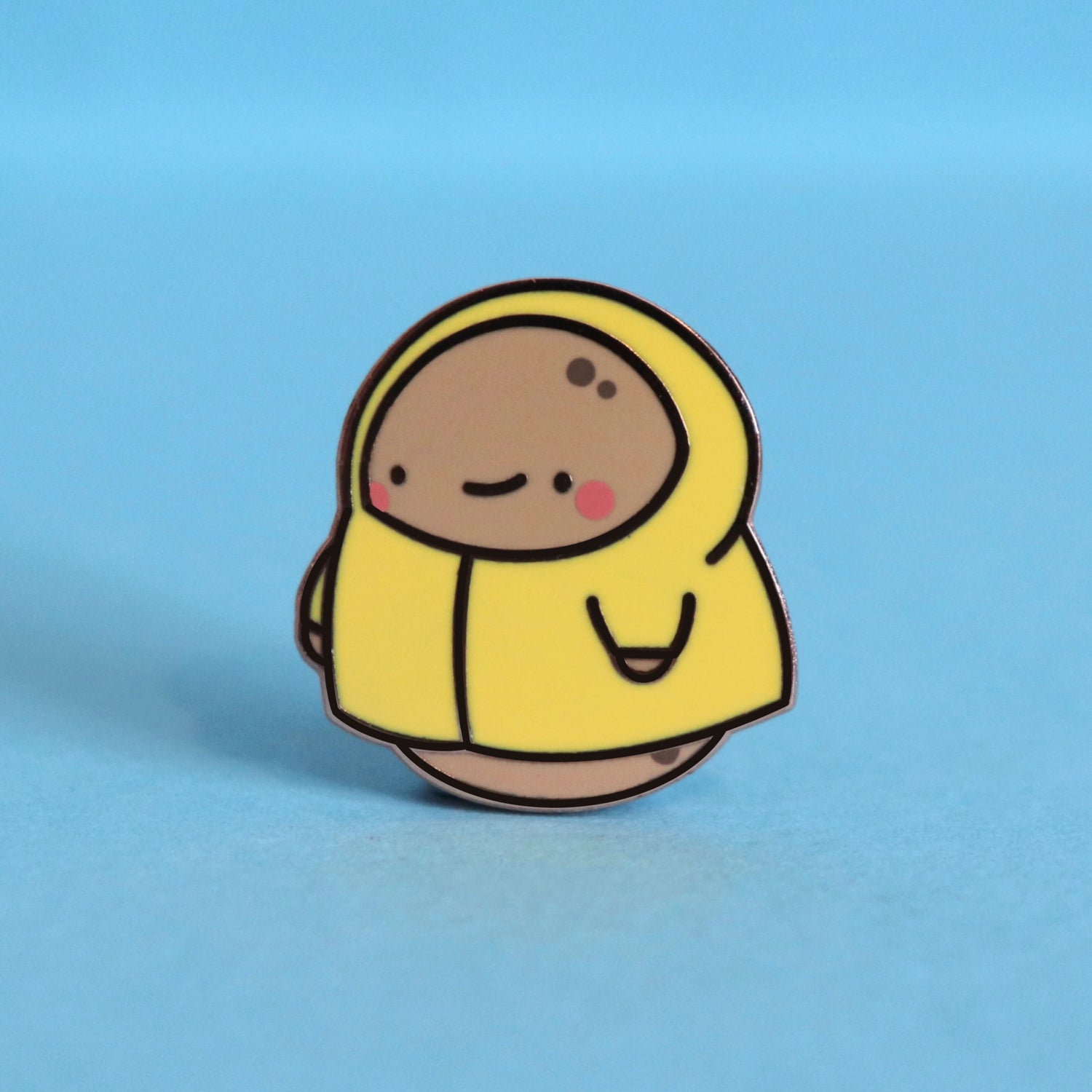 Potato in a raincoat enamel pin on blue table