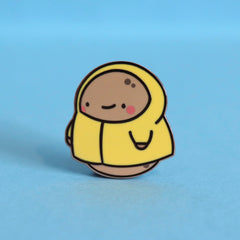 Potato in a raincoat enamel pin on blue table