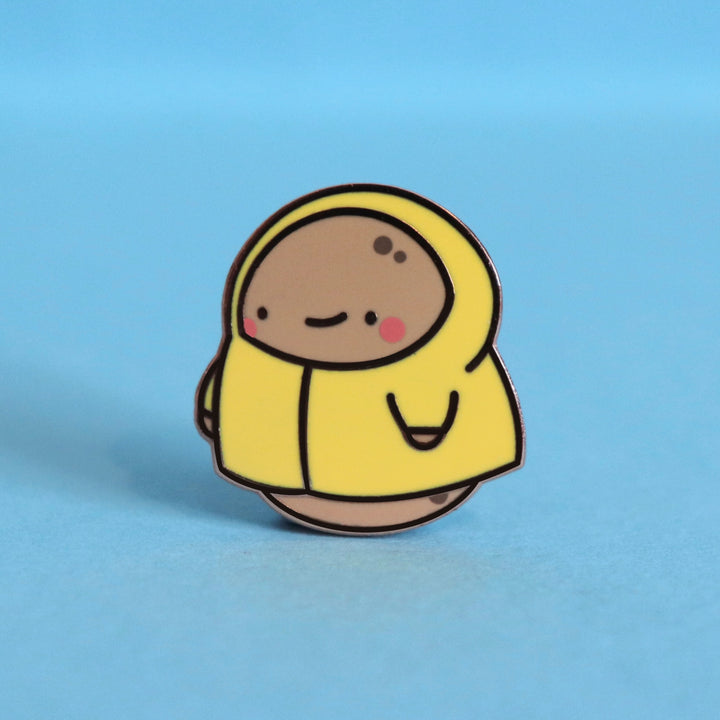 Potato in a raincoat enamel pin on blue table