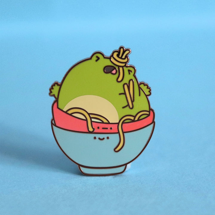 Frog in a bowl enamel pin on blue table