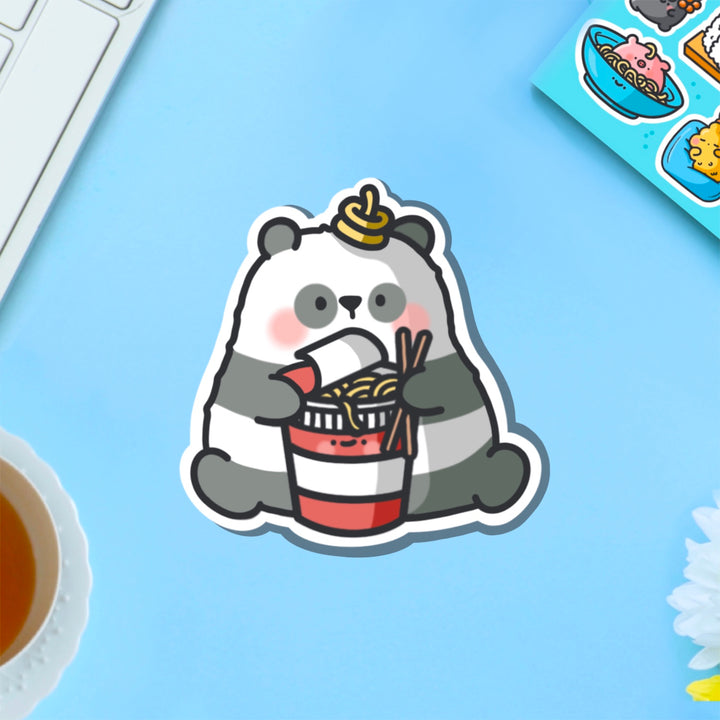 Panda holding ramen vinyl sticker on blue table