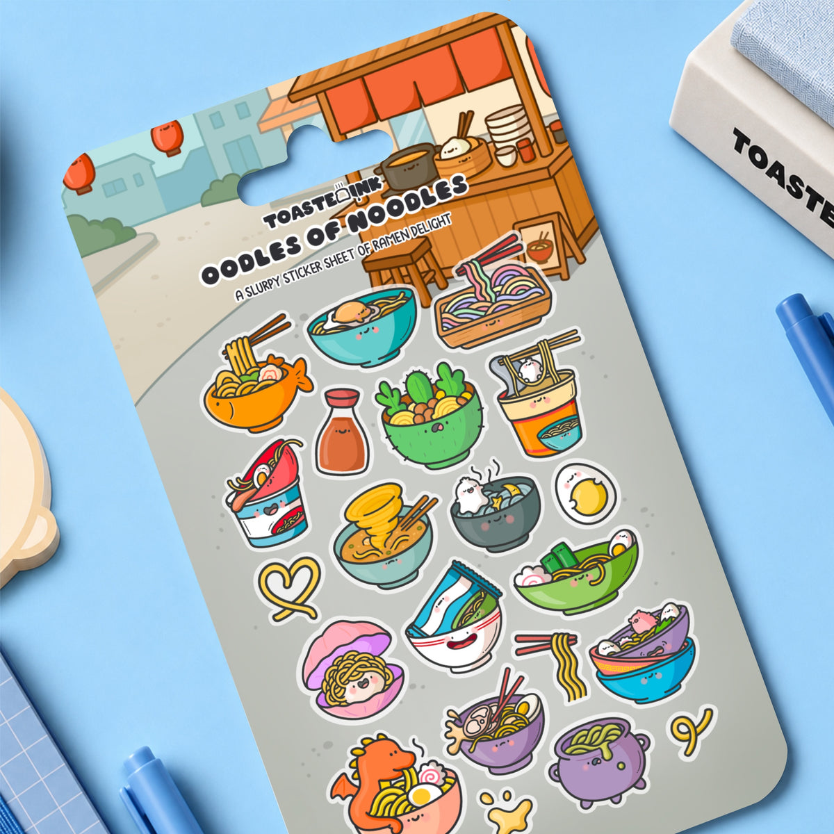 Ramen stickers on blue desk with notebooks and stationery