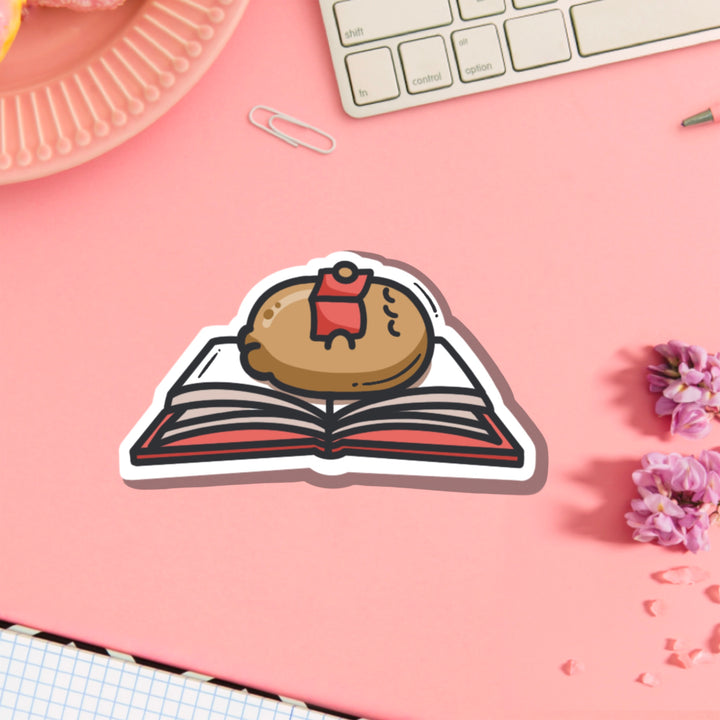 Potato reading a book vinyl sticker on pink table