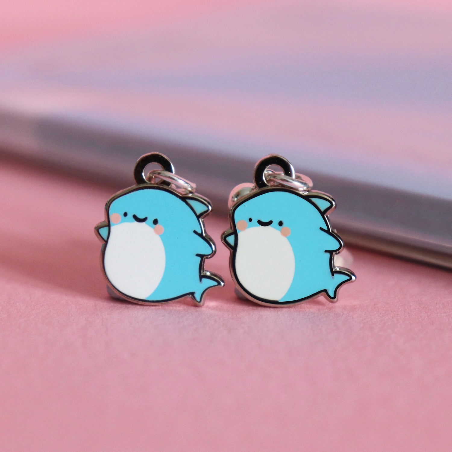 Shark earrings on pink table with notepad