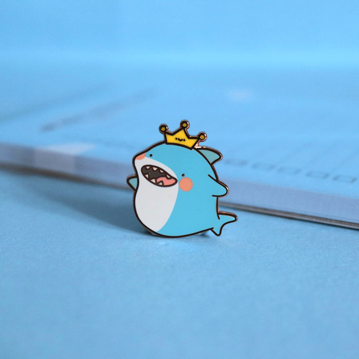 Shark enamel pin on blue background with notepad