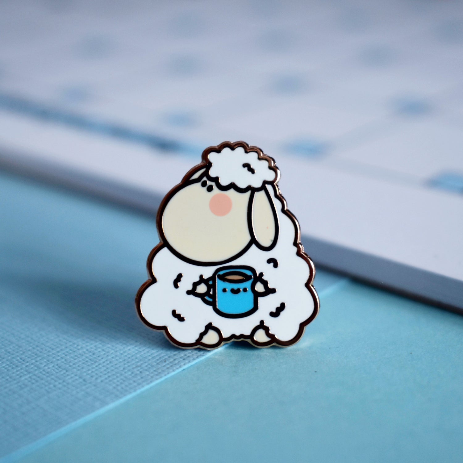Sheep enamel pin on blue table