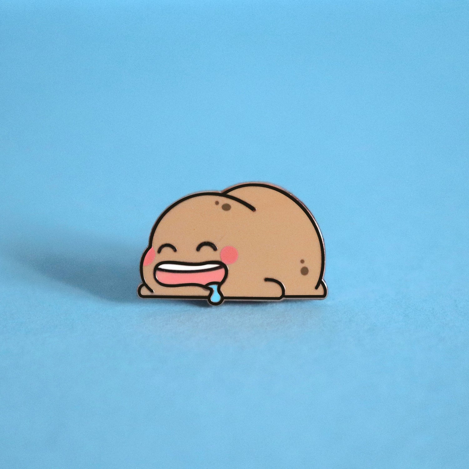 Sleeping potato enamel pin on blue background