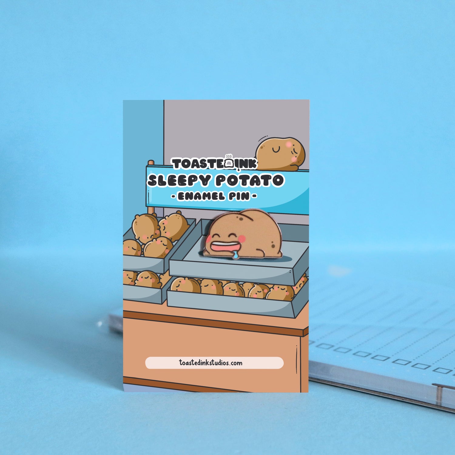 Sleeping potato enamel pin on backing card with notepad
