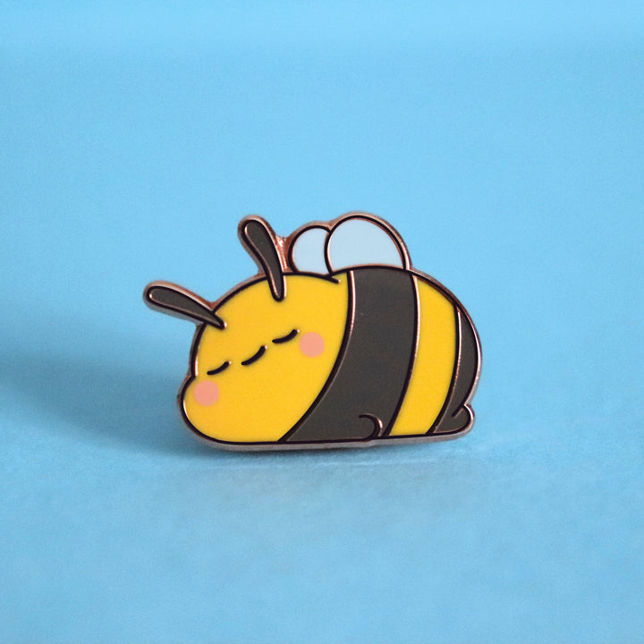 Sleeping bee enamel pin on blue desk