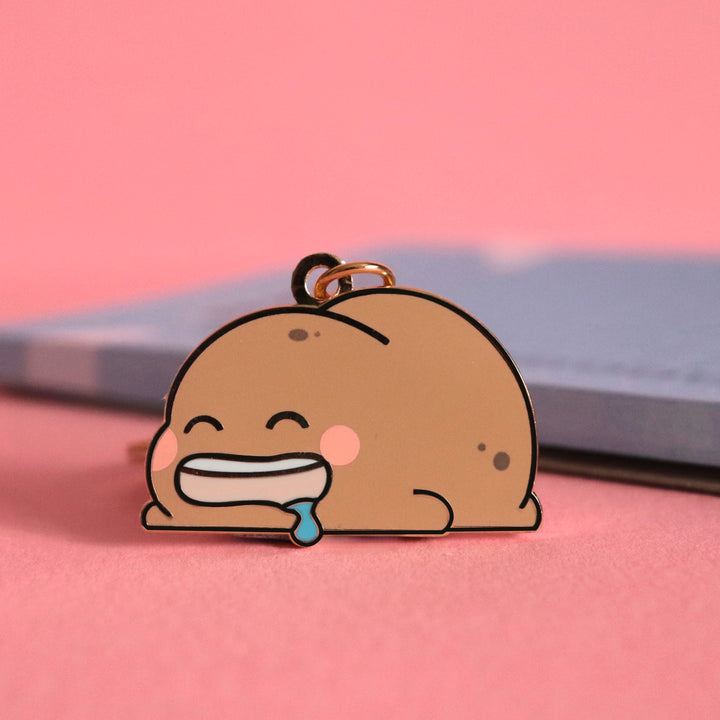 Potato keyring on pink table with notepad
