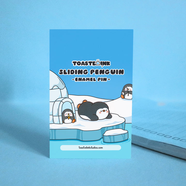 Penguin sliding on his belly enamel pin on ice backing card