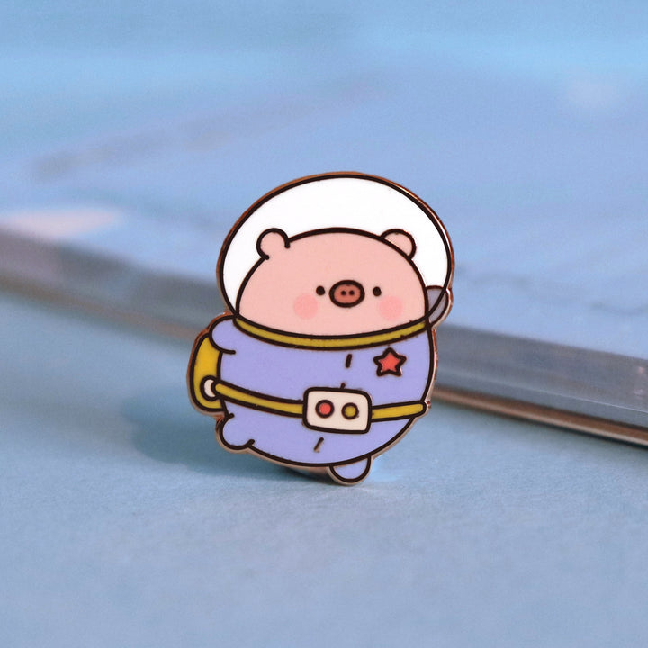 Space Pig enamel pin on blue background with deskpad