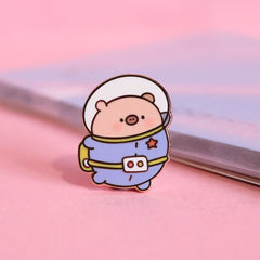 Space Pig enamel pin on pink table with notepad