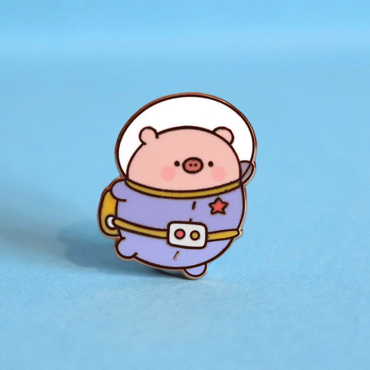 Space Pig enamel pin on blue table