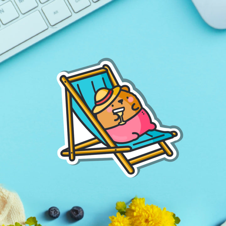 Bear sunbathing vinyl sticker on blue table with keyboard