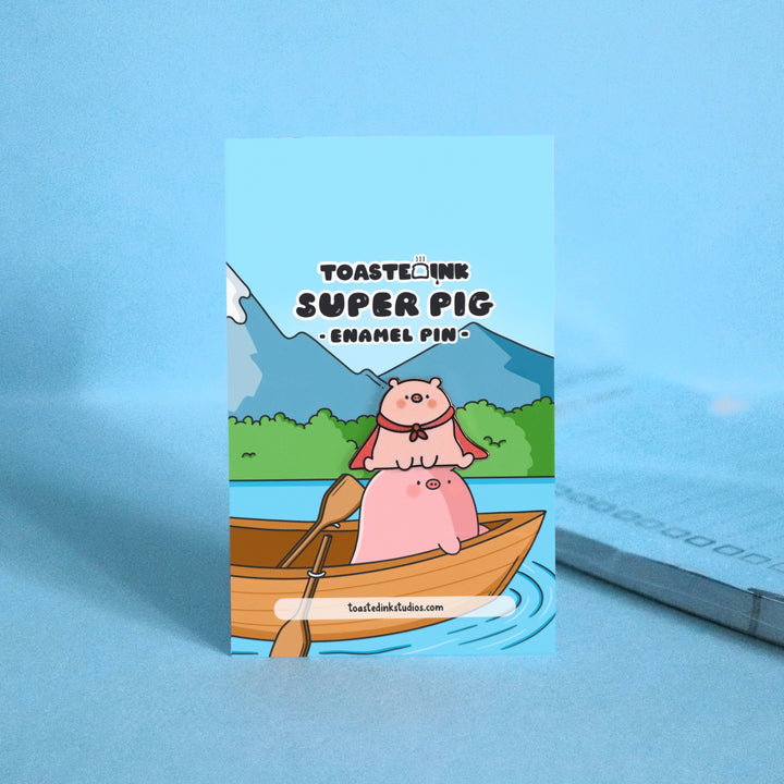 Super pig wearing red cape enamel pin on pigs head in a boat backing card