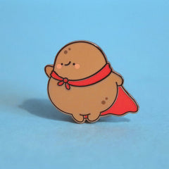 Super potato in red cape enamel pin on blue table