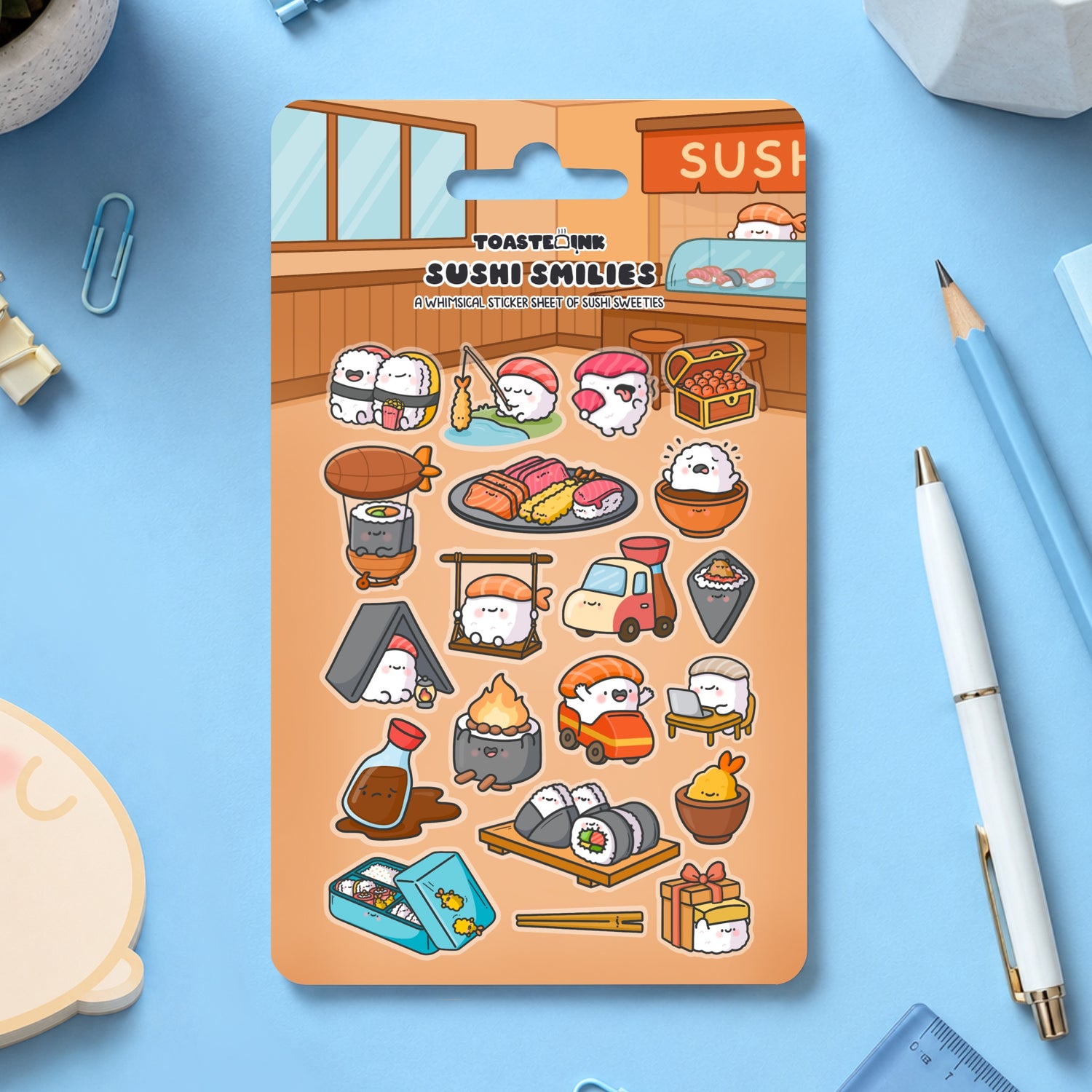 Sushi sticker sheet on blue table scattered with stationery
