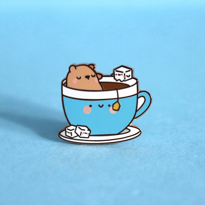 Bear sat in a cup of tea enamel pin on blue background