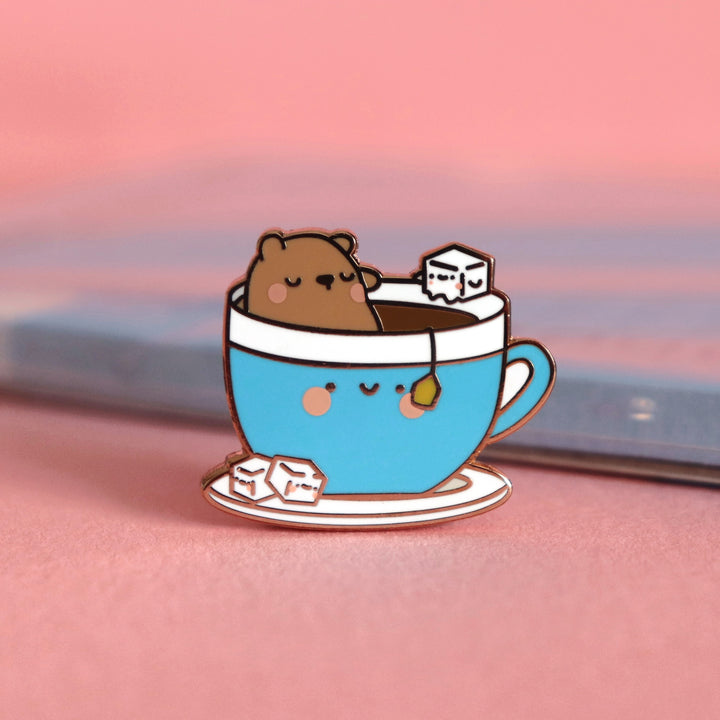 Bear sat in a cup of tea enamel pin on pink table