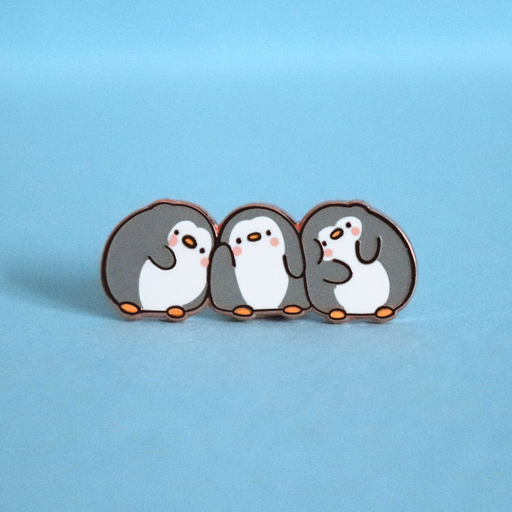 Three penguins enamel pin on blue desk