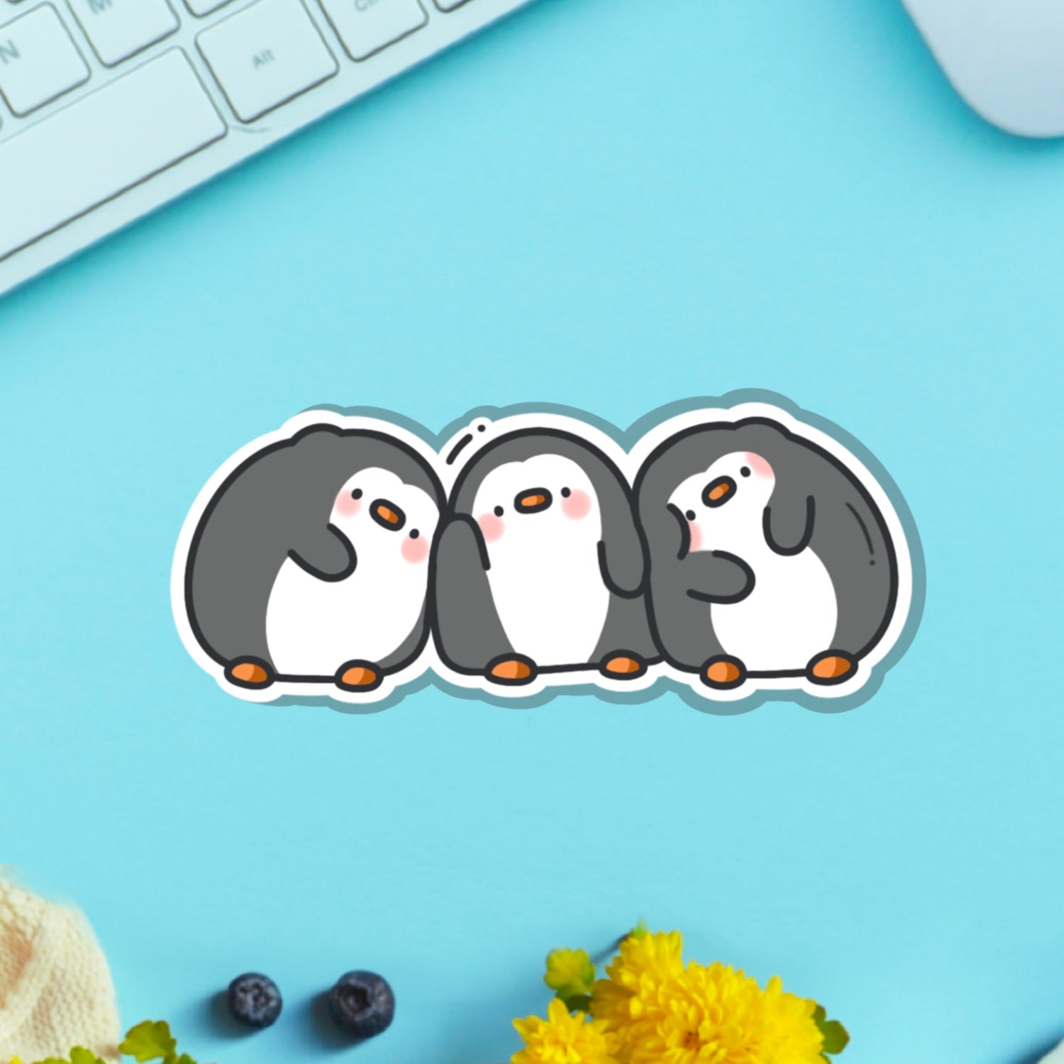 Three penguins vinyl sticker on blue table with keyboard