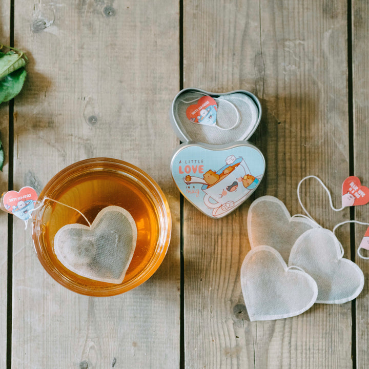 Heart shaped tea bag and tin on wooden table