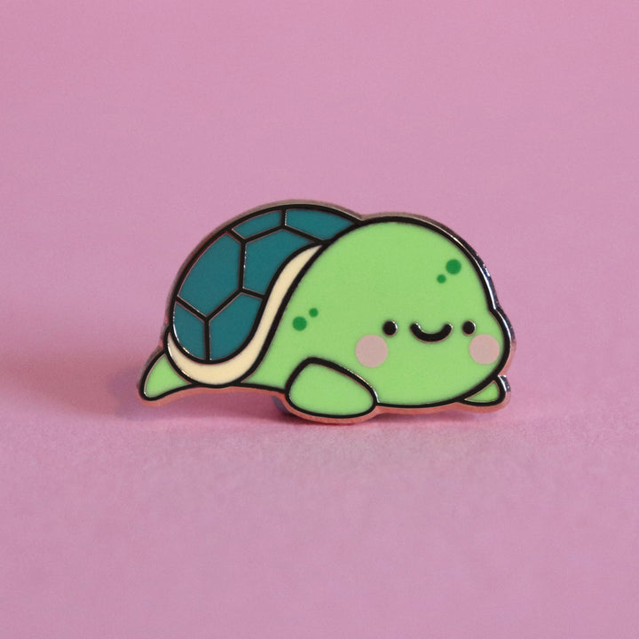 Turtle enamel pin on pink table