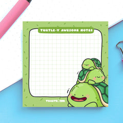 Turtle sticky notes on blue and white table with pink pen