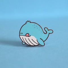 Whale enamel pin on blue desk