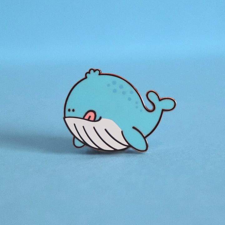 Whale enamel pin on blue desk