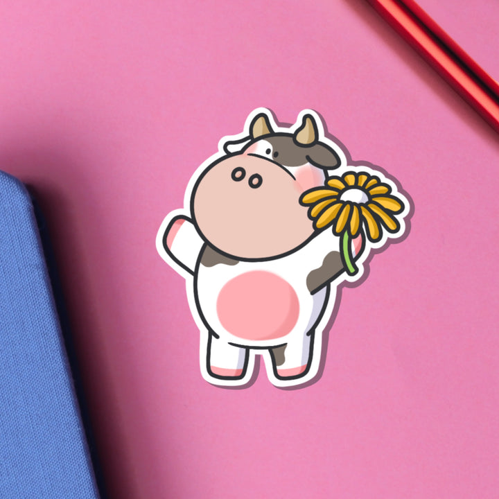 Cow holding flower vinyl sticker on pink table