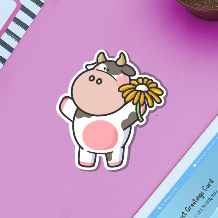 Cow holding flower vinyl sticker on purple table with ipad