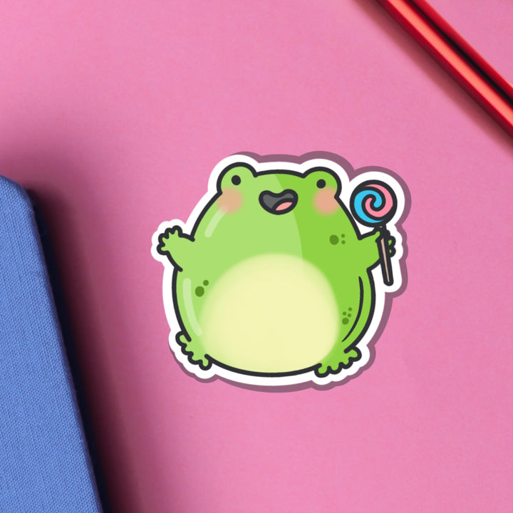 Jumping frog vinyl sticker on pink table with notebook