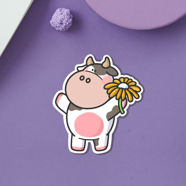 Cow holding flower vinyl sticker on purple table