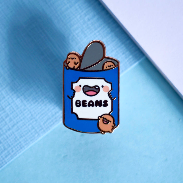 Cute Beans Enamel Pin on a blue background