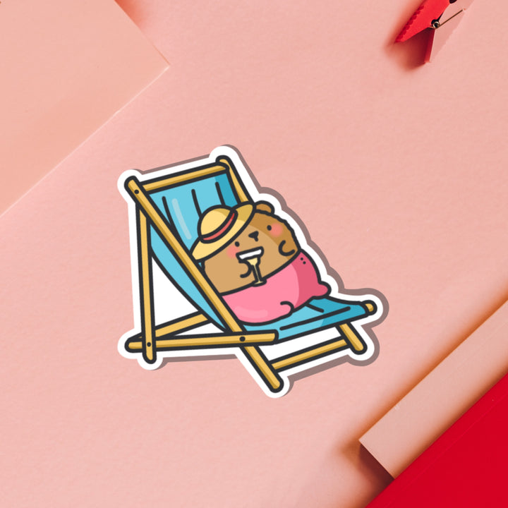 Bear Sunbathing vinyl sticker on pink table and notebook