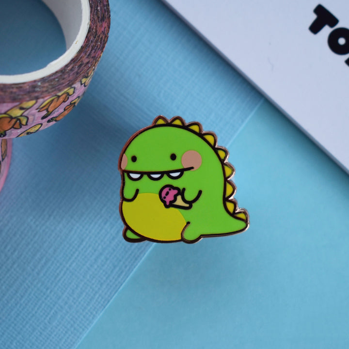 Dinosaur pin with washi tape and notepad on blue table