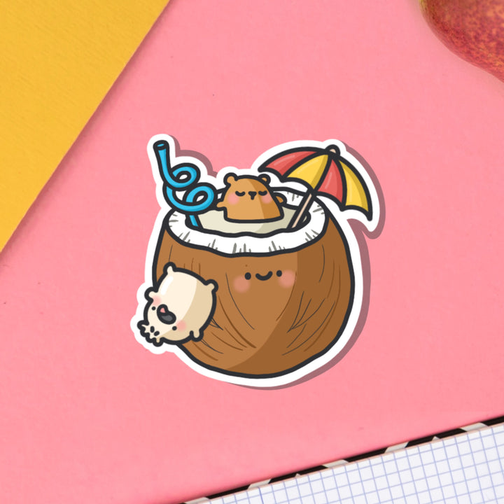 Bear bathing in coconut vinyl sticker on pink table and notebook