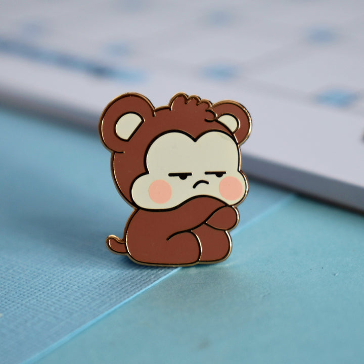 Grumpy monkey lapel pin on blue table