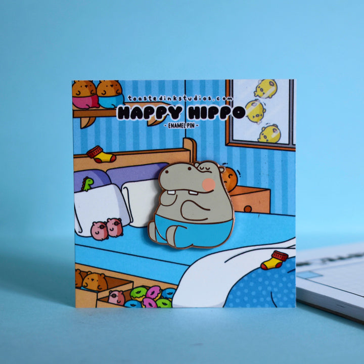 Hippo enamel pin on bed backing card and blue table