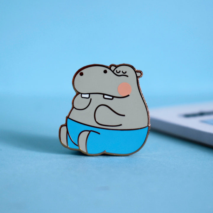 Hippo enamel pin on blue background and notebook