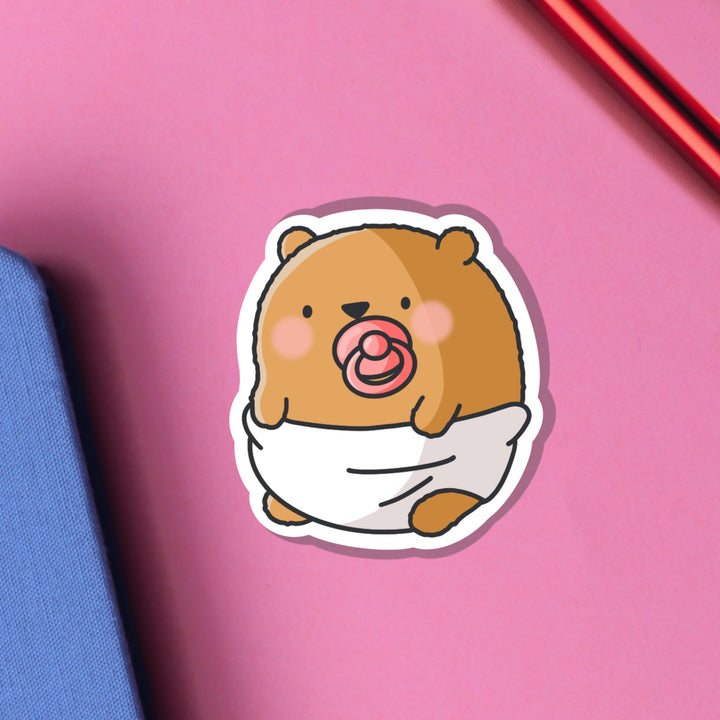Bear dressed as baby vinyl sticker on pink table 