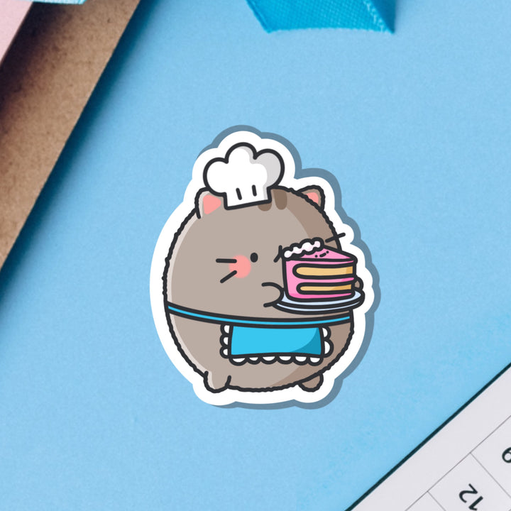 Cat holding cake vinyl sticker on blue background