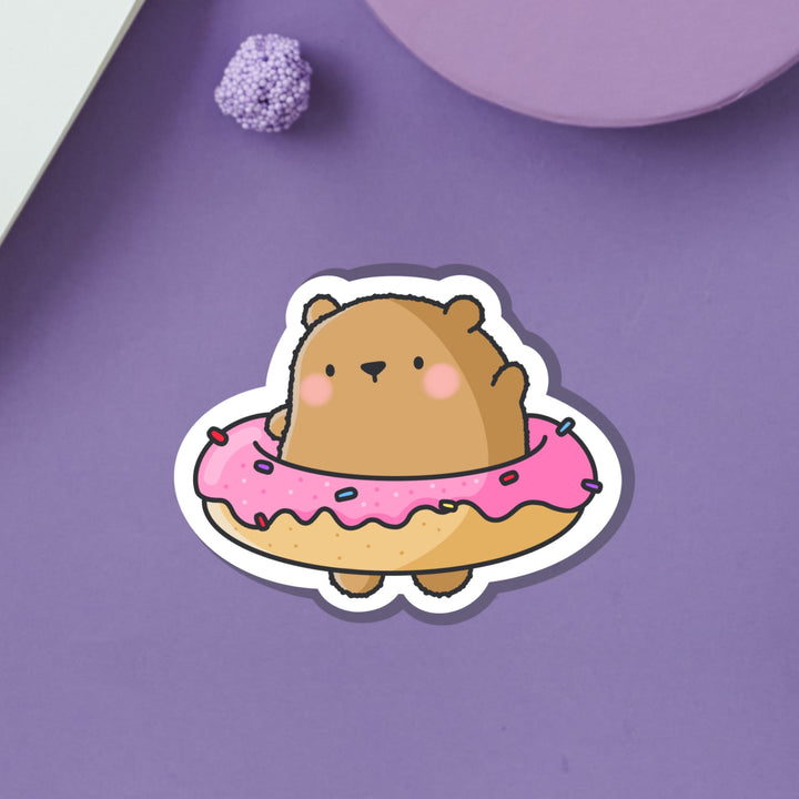 Bear wearing a donut vinyl sticker on purple table