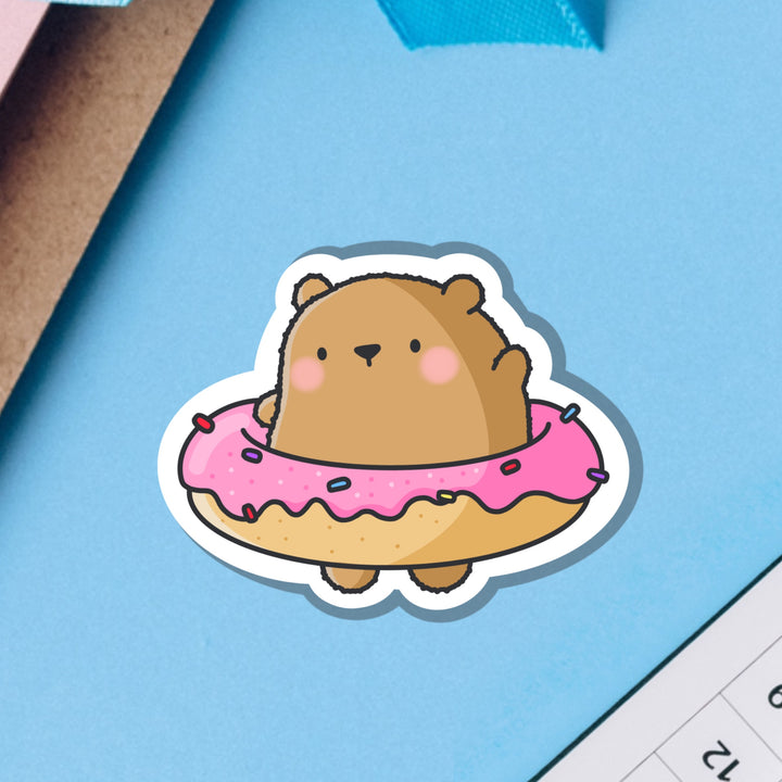 Bear wearing a donut vinyl sticker on blue table